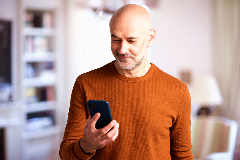 A middle-aged man looks at his phone, feeling reassured.