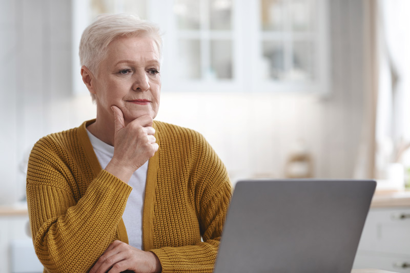 A senior woman using her laptop to research online and learn more about the cataract surgery procedure.